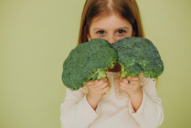 Criança segurando brócolis
