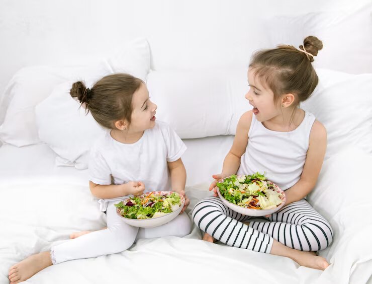 Duas crianças comendo salada